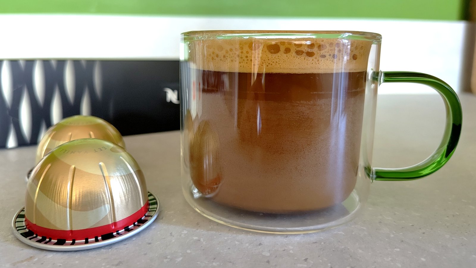 Nespresso Sweet Vanilla Decaf pods with mug of brewed coffee